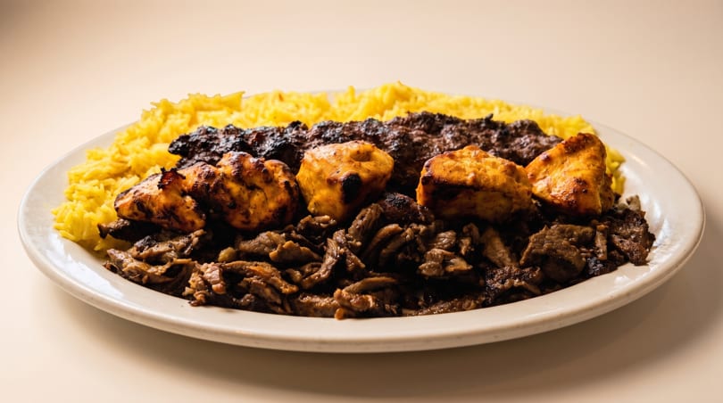 Plate of yellow rice, grilled chicken, ground meat kabob, and sliced meat.