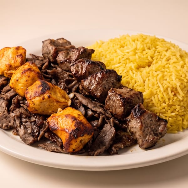 Plate of yellow rice, sliced beef, and grilled chicken and beef kebabs.
